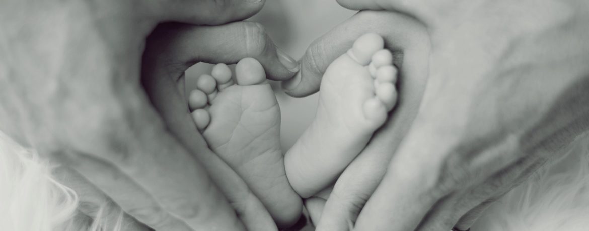 babyvoeten omvouwen door de handen van de ouders in de vorm van een hart